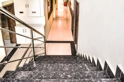 eine Treppe in einem Gebäude mit schwarzen Marmorböden und weißen Wänden in der Unterkunft Capital O Jai Adisson in Cuttack