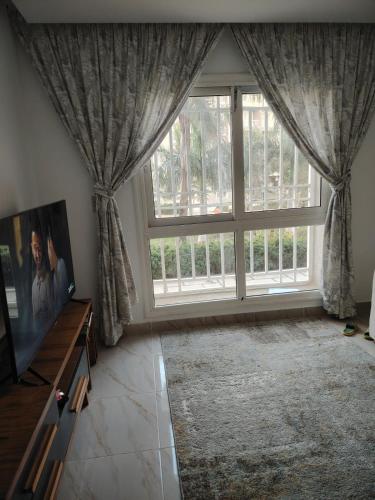 a living room with a large window with curtains at Cozy Furnished apartment in new Cairo in Madinaty