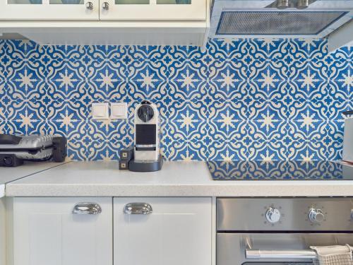 a kitchen with blue and white tiles on the wall at Luxurious House Vasiliki with great view in Hydra