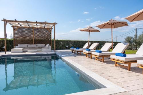 a swimming pool with lounge chairs and umbrellas next to a pool at Magnolia Mansion in Kalamata