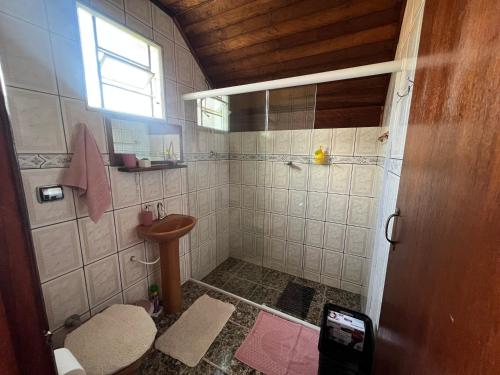 Un baño con ducha, lavabo e inodoro. en Chalé Rosa Mística, en São Bento do Sapucaí