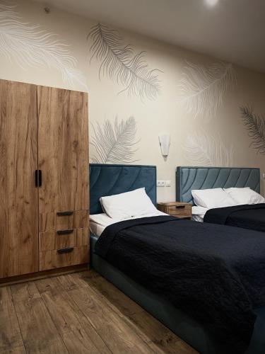a bedroom with two beds and a wooden cabinet at Міні-готель Тремпель in Kharkiv