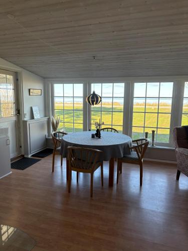 a dining room with a table and chairs and windows at Djursland Lystrup Strand Ferieboliger in Allingåbro