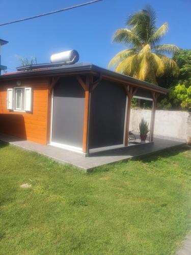 a house with a garage and a palm tree at Bungalow vacances in Sainte-Rose