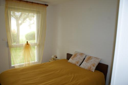 - une chambre avec un lit doté d'un couvre-lit jaune et d'une fenêtre dans l'établissement VANNES Les JARDINS DU PORT, à Vannes