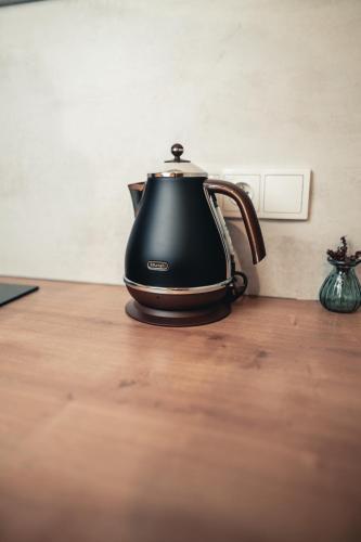 a black tea kettle sitting on a wooden table at Rezidence Magnolie in Velké Pavlovice