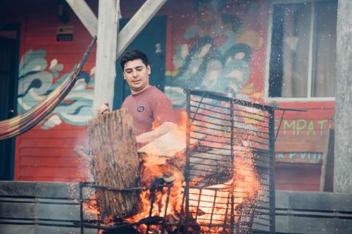 a man is standing next to a fire at Compay Hostel Punta del Diablo in Punta Del Diablo