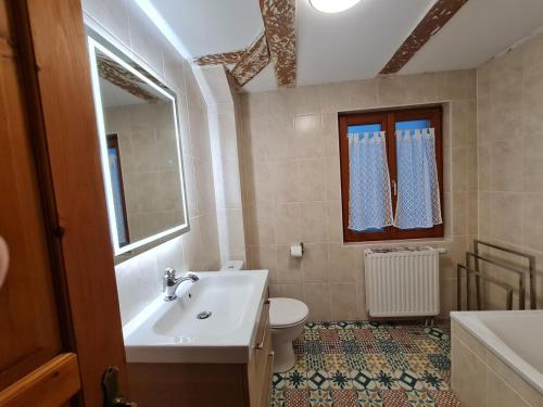a bathroom with a sink and a toilet and a mirror at Gîte La Ferme des Délices in Epfig