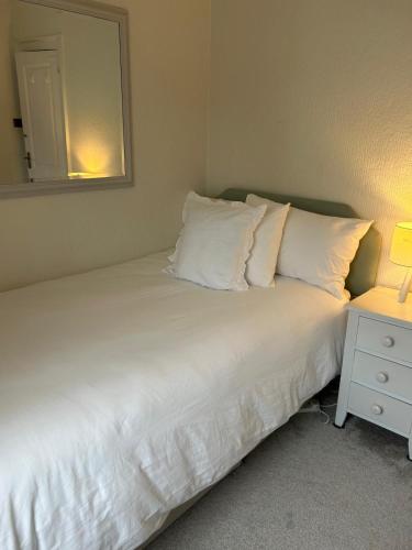 a bed with white pillows and a mirror in a room at Single Room in Georgian Masionette in Blandford Forum