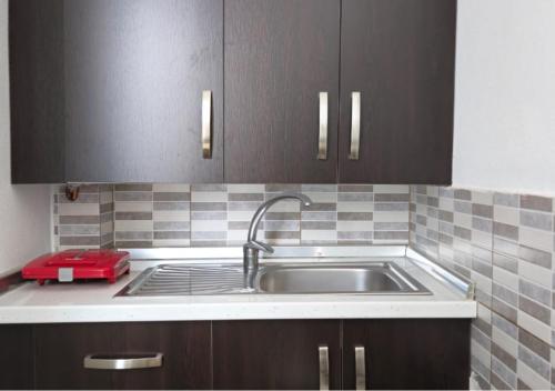 a kitchen with a sink and brown cabinets at Guest House Pogradeci in Pogradec