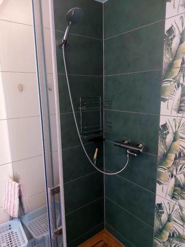 a shower with a shower head on a green tile wall at U Andrzeja i Ewy in Kocioł