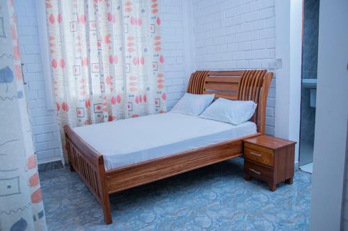 ein Bett mit einem Bettrahmen aus Holz und einem Tisch in der Unterkunft Entire home in Mlole, Kigoma, Tanzania in Gungu