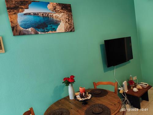 a dining room with a table and a tv at Palm garden paradise in Pervolia