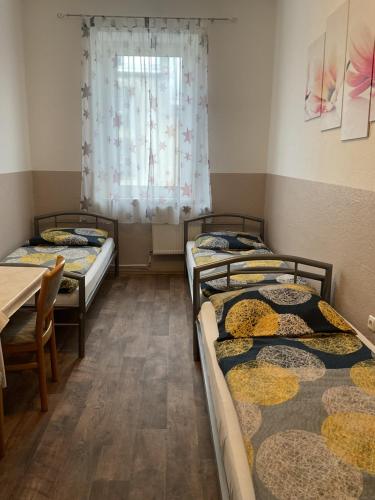 a room with three beds and a table and a window at Pension&Hostel Anna - Monteurzimmer -------- 10 minutes walk to Oktoberfest in Munich