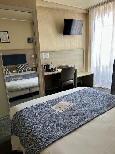 a hotel room with a mirror and a bed and a desk at Cit'Hotel le Challonge in Dinan