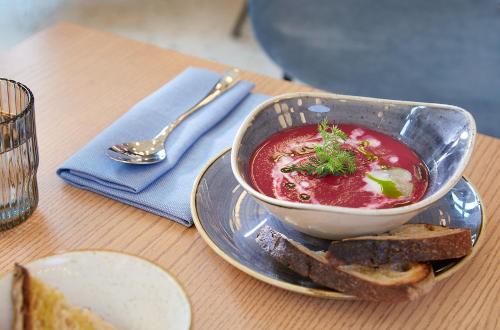 a bowl of soup on a plate with bread and a spoon at Novotel Hamburg Central Station in Hamburg