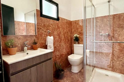 a bathroom with a toilet and a glass shower at Casa dos Andrés in Calheta