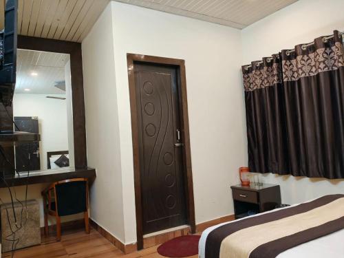 a bedroom with a bed and a door and a mirror at TRPOTELS Sudarsan in Haridwār