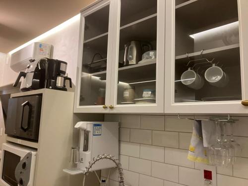 a kitchen with white cabinets with pots and pans at Apart-hotel Theotókos Flats in Piumhi
