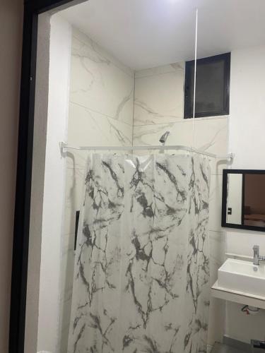 a bathroom with a marble shower curtain and a sink at Hotel Boutique Manta in Los Ayala