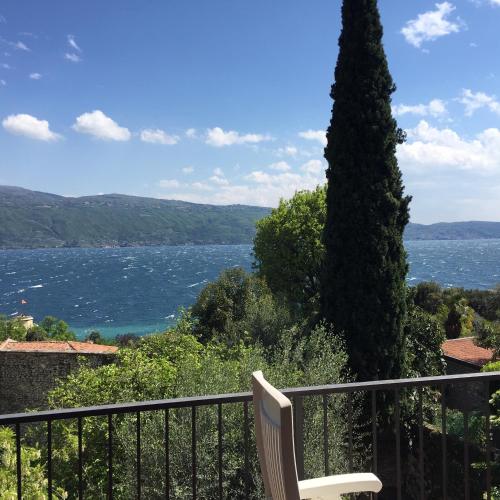a white chair sitting on a balcony overlooking the water at Casa Ileana in Gargnano