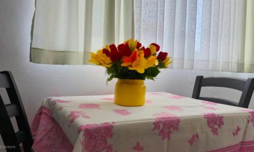 a yellow vase filled with flowers sitting on a table at Guest House Pogradeci in Pogradec