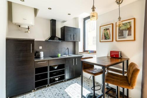 une cuisine avec des armoires noires et une table avec des chaises dans l'établissement Cosy et spacieux T2 en ville - paradis centre-ville, à Marseille
