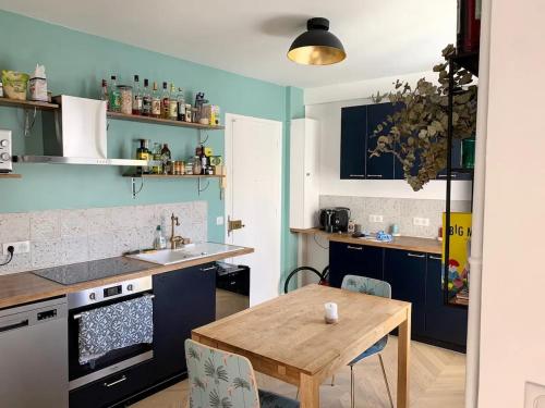 une cuisine avec des murs bleus et une table en bois dans l'établissement New & cosy beautiful apt close Marais!, à Paris