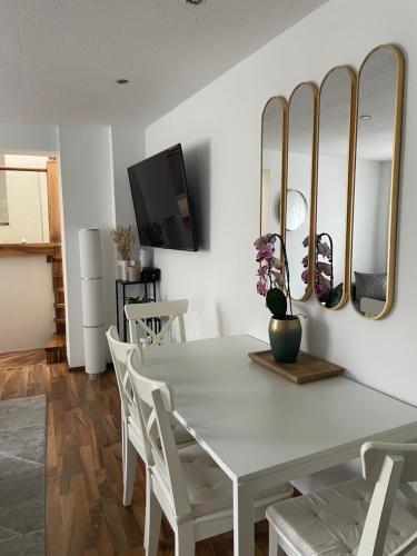 biała jadalnia z białym stołem i lustrami w obiekcie Orchideen Apartment w Villach