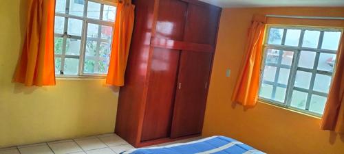 a bedroom with an orange door and two windows at Casa Tlatlauqui in Xotiocuautitla