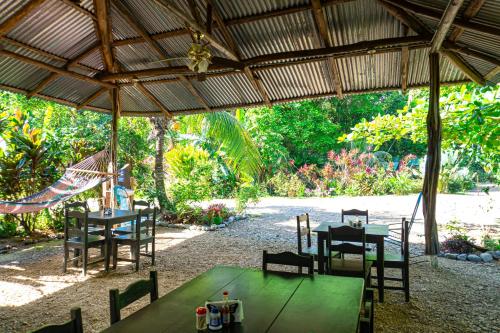 a restaurant with tables and chairs under a roof at Citronela Lodge Corcovado in Drake