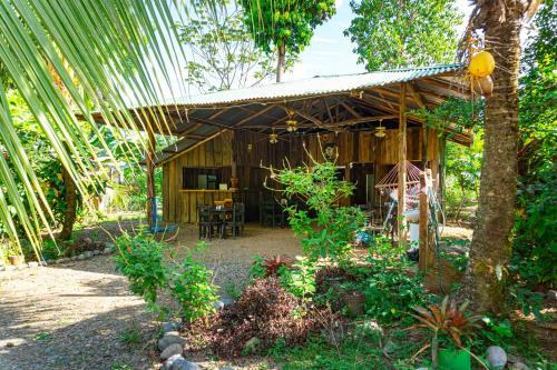 a wooden cabin with a table and chairs in a garden at Citronela Lodge Corcovado in Drake