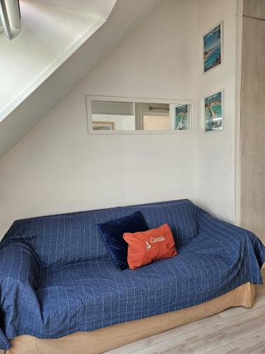 - un canapé bleu avec un oreiller rouge dans l'établissement Studio neuf à proximité de Saint-Malo, à 2km des plus belles plages de la côte d'Emeraude, à Saint-Coulomb