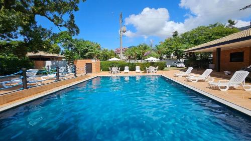 een zwembad met witte stoelen en een zwembad bij Flat Maresias Beira Mar in Maresias