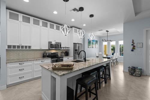 una cocina con armarios blancos y una gran isla con taburetes. en Sunrise Island Retreat, en Fort Pierce