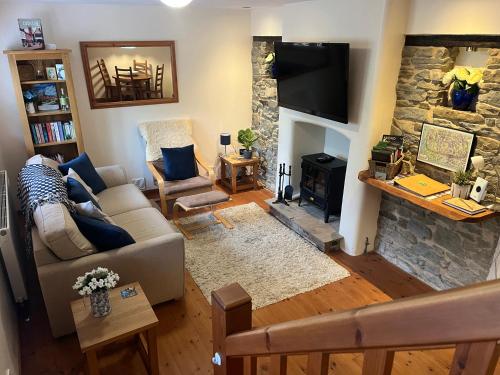 a living room with a couch and a stone fireplace at Frog Cottage, Ludlow - a charming townhouse for 4 in Ludlow