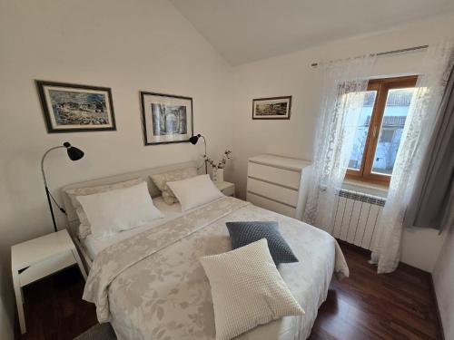 biała sypialnia z łóżkiem i oknem w obiekcie Apartment PARENZANA, little row HOUSE with big green yard in central Istria w mieście Rakotule