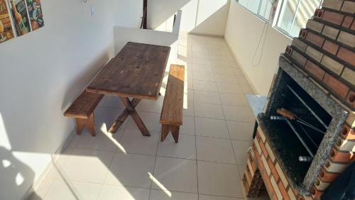 a wooden bench sitting in the corner of a room with a fireplace at Casa Brisa Nordeste in Palhoça