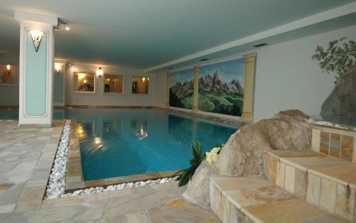 a large swimming pool in a house with a rock wall at Residence Pez Gajard in San Martino di Castrozza