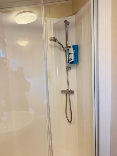 a shower stall in a bathroom with a sink at Little Cha-Am Caravan Hire at Silver Sands in Lossiemouth