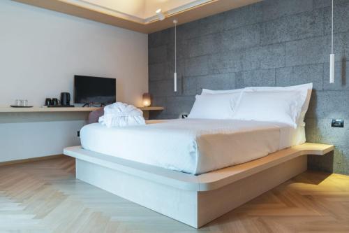 a bedroom with a large white bed with a wall at Bahal dell'Etna Agri-Resort in Ramacca
