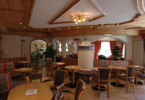 a restaurant with tables and chairs and a chandelier at Residence Pez Gajard in San Martino di Castrozza