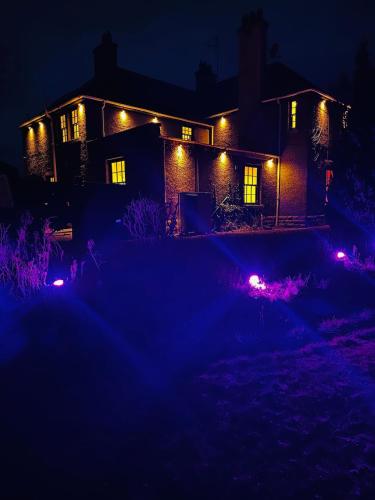 a house lit up at night with lights at Red Roofs - 5BR Luxury - Large Gardens - EV Point - Near Edinburgh in Newtongrange