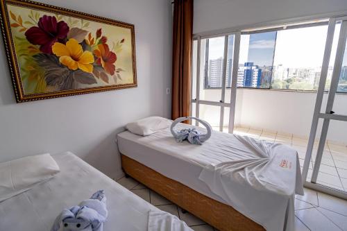 um quarto com uma cama e uma pintura na parede em ADTUR Flats CTC - Condomínio Saphire ou Center Caldas em Caldas Novas