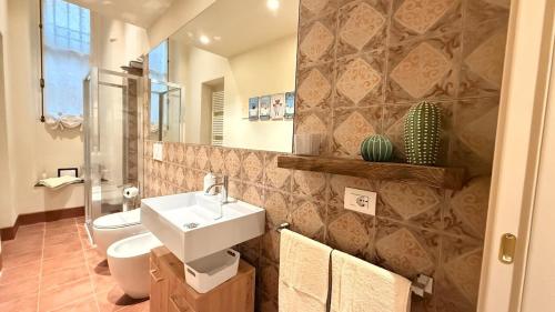 ein Badezimmer mit Waschbecken, Toilette und Spiegel in der Unterkunft Residenza Palazzo Gherardi in Parma