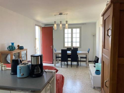 une cuisine et un salon avec une table et des chaises dans l'établissement Un Jardin Terrasse sur la Mer, à Port-Vendres