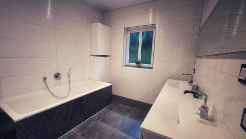 a white bathroom with a tub and a sink at Fietes Achternutkiek in Mellenthin