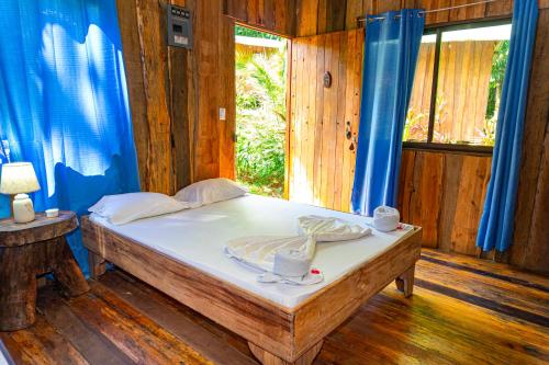 a bedroom with a bed with blue curtains and a window at Citronela Lodge Corcovado in Drake