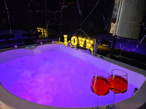 two wine glasses in a bath tub with purple lighting at Setteabbracci Suite & Apartments in Baronissi