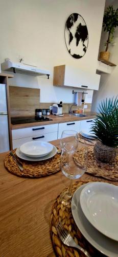 a wooden table with plates and wine glasses on it at L'Original, Superbe appartement à 5min de la plage in Zonza